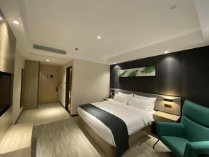 a hotel room with a bed and a green chair at Thank Inn Plus Yancheng Sheyang Dayang Road in Sheyang