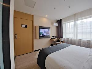 a hotel room with a bed and a flat screen tv at Thank Inn Plus Lanzhou Dongfanghong Plaza Pingliang Road in Lanzhou