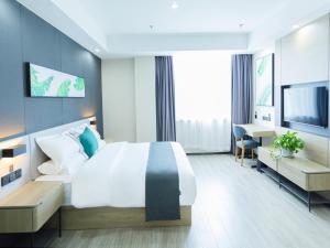 a hotel room with a large bed and a desk at Thank Inn Plus Xing'an Senfa Four Season Flower City in Ulanhot