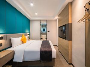 a bedroom with a large bed and a television at Feronia Hotel Beijing Bird's Nest Datun Road in Beijing
