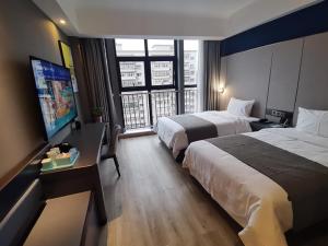 a hotel room with two beds and a flat screen tv at Thank Inn Plus Hanzhong High-Speed Railway Station in Hanzhong
