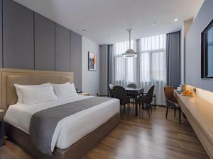 LanOu Hotel Qianjiang High-Speed Railway Station Lobster City في Qianjiang: غرفة فندقية بسرير كبير وطاولة