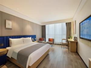 um quarto de hotel com uma cama e uma televisão de ecrã plano em LanOu Hotel Taikoo Li Night Market Kuqa City em Kuqa