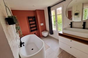 a bathroom with a large white tub and a sink at Les Jardins de Rosie in Arthies +17 photos