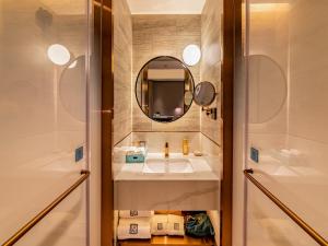 a bathroom with a sink and a mirror and a shower at LanOu Hotel Fuzhou Changle District Changle Airport in Fuzhou
