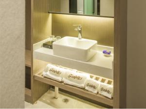 a bathroom with a sink and towels on a shelf at Junyi Hotel Jizhou District East Yangming Road in Ji'an