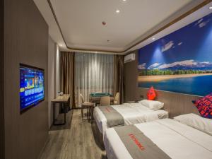 um quarto de hotel com duas camas e uma televisão de ecrã plano em Junyi Hotel Jizhou District East Yangming Road em Ji'an