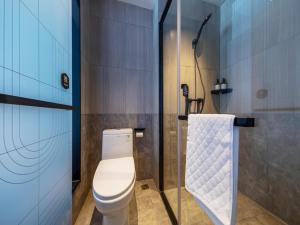 a bathroom with a toilet and a shower with a towel at Thank Inn Linyi Jiaxing Fruit Market in Linyi