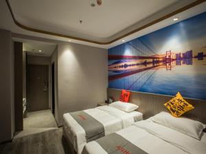 sypialnia z 2 łóżkami i obrazem na ścianie w obiekcie Junyi Hotel Jizhou District East Yangming Road w Ji'an