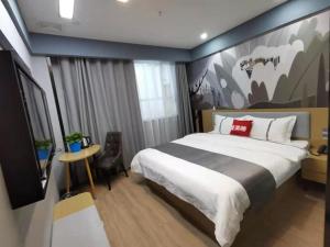 a bedroom with a large bed with a painting on the wall at Thank Inn Plus Korla Saybag Market in Korla