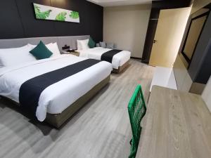 a hotel room with two beds and a green chair at Thank Inn Plus Aksu Kuqa Xingfu Road in Kuqa
