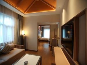 ein Wohnzimmer mit einem Sofa und einem Flachbild-TV in der Unterkunft Feronia Hotel Taihang Xiyagou Tourist Area in Nanhekou