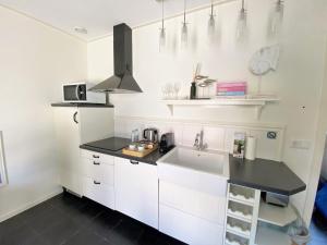 a kitchen with white cabinets and a sink at DJP76 mooi gelijkvloers appartement met terras in Domburg
