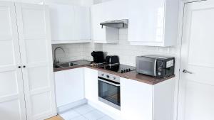 a white kitchen with a microwave and a stove at Baker Street Central Apartments in London