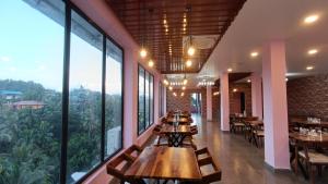 a restaurant with tables and chairs and large windows at Hotel King Safire in Port Blair