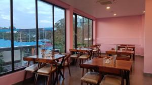 a restaurant with wooden tables and chairs and large windows at Hotel King Safire in Port Blair