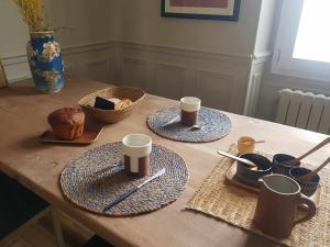 een houten tafel met twee borden en kopjes erop bij la maison haute in Toucy