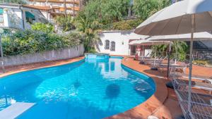 une grande piscine bleue avec un parasol dans l'établissement Bobby Executive, à Sanremo