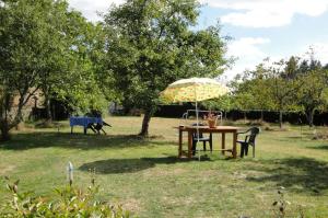einen Tisch und Stühle mit Sonnenschirm im Hof in der Unterkunft Vedeix in Saint-Auvent