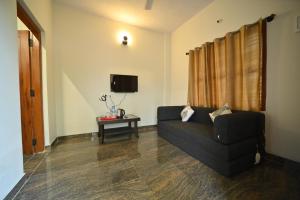 salon z czarną kanapą i telewizorem w obiekcie Coorg HomeStay Resort w mieście Kushalanagar
