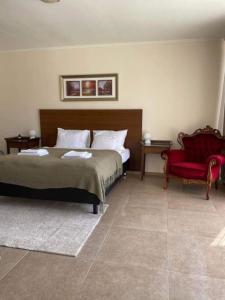 1 dormitorio con 1 cama y 1 silla roja en Vitál Guesthouse, en Almamellék