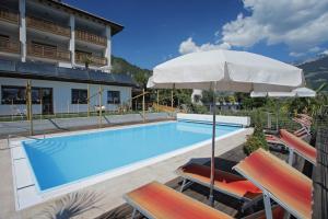 einem Pool mit Stühlen und einem Sonnenschirm neben einem Gebäude in der Unterkunft Hotel Garni Paler in Dorf Tirol
