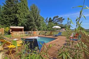 a backyard with a pool and a wooden deck at La cle des champs 