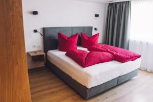 een slaapkamer met een bed met rode kussens bij Das Gschossmann in Saalbach Hinterglemm