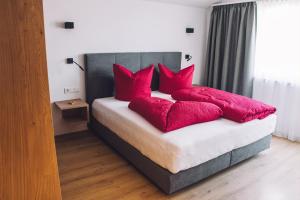 ein Schlafzimmer mit einem Bett mit roten Kissen in der Unterkunft Das Gschossmann in Saalbach-Hinterglemm