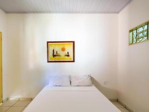 uma cama num quarto branco com uma fotografia na parede em Pousada Caldas Novas em Caldas Novas