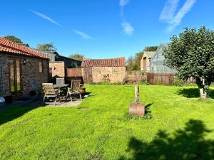 un patio con mesa y sillas en el césped en Morndyke Cottage en Thirsk