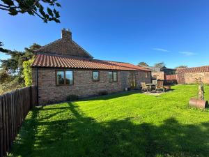 a brick house in a yard with a grass field at Morndyke Cottage in Thirsk