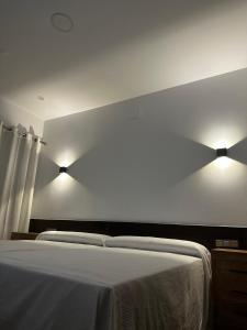 a bedroom with a bed with two lights on the wall at Hotel Rural Irina in Badajoz