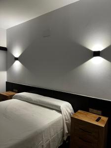 a bedroom with a bed and two lights on the wall at Hotel Rural Irina in Badajoz