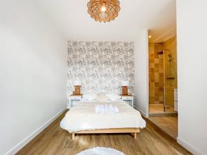 a white bedroom with a bed and a chandelier at Hyper-centre de Grenoble, suite parentale - wifi fibre - cocon in Grenoble