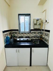 uma cozinha com armários brancos, um lavatório e uma janela em 1BR Apartment Parel em Mumbai