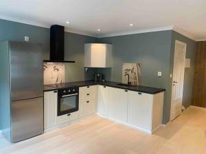 a kitchen with white cabinets and a black counter top at Moderne og velutstyrt leilighet nær sentrum in Sandefjord