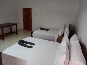 a room with two beds and a table and a room with two beds at LLT Tourist Inn and Safari Jeep in Wilpattu