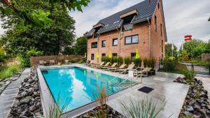 a swimming pool in front of a brick building at Elbstrand Resort Krautsand - Hotel Elbstrand in Drochtersen