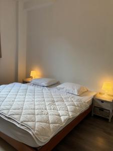 - un lit dans une chambre avec 2 lampes sur 2 tables dans l'établissement Belle époque à 5mn de la plage, à La Panne