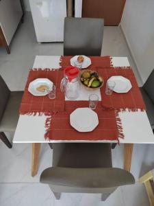 une table rouge avec des assiettes et un bol de fruits dans l'établissement Novo ap. João Pessoa!, à João Pessoa