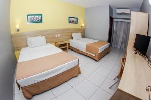 um quarto de hotel com duas camas e uma televisão de ecrã plano em Gree Hotel em São Luís