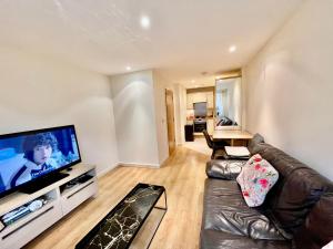 a living room with a couch and a flat screen tv at Cosy apartment in West London in London