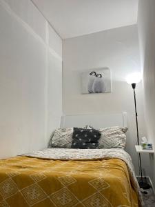ein weißes Schlafzimmer mit einem Bett mit einer gelben Decke in der Unterkunft Tanih Place in Abu Dhabi