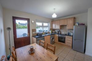 a kitchen with a wooden table and a refrigerator at Waterfall Cottage in Carnlough