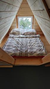 uma cama num quarto de madeira com uma janela em Domek drewniany Szafran em Witów