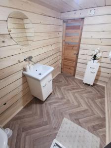 a bathroom with a white sink and wooden walls at Domek drewniany Szafran in Witów