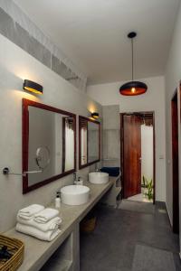 a bathroom with two sinks and two mirrors at Savera Beach Houses in Jambiani