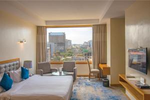 ein Hotelzimmer mit einem Bett und einem großen Fenster in der Unterkunft Golden Tulip Westlands Nairobi in Nairobi