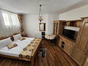 - une chambre avec un lit, une table et une télévision dans l'établissement Pensiunea Nobil Medieval, à Sighişoara